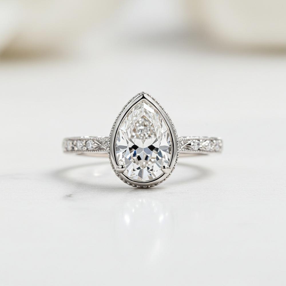 Elegant bezel set pear engagement ring with a sleek metal rim surrounding a stunning pear-shaped diamond