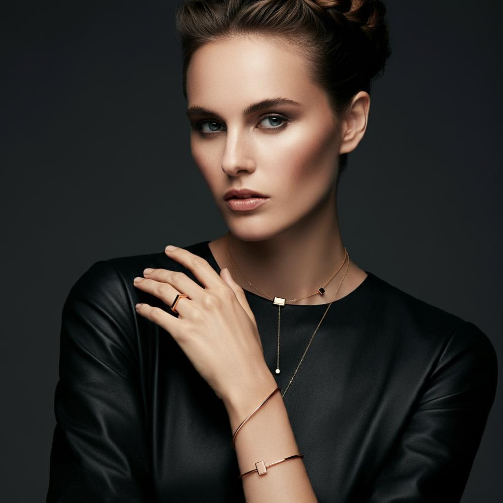 A woman elegantly adorned with layered necklaces and stackable rings, showcasing how jewelry complements personal style.