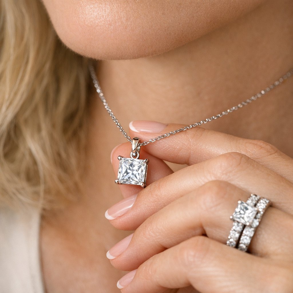 Stack of wedding bands next to a princess-cut diamond engagement ring on a white surface