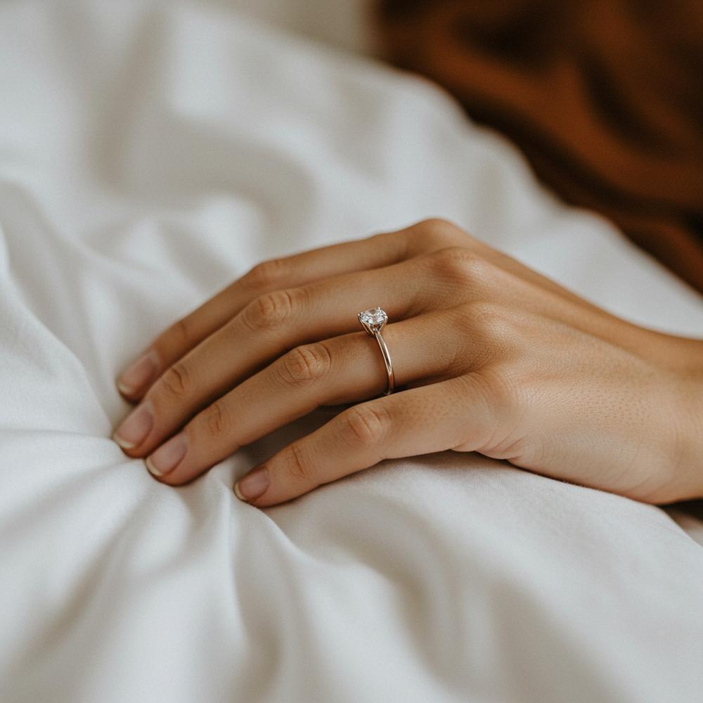 Woman's hand with diamond engagement ring resting on a pillow