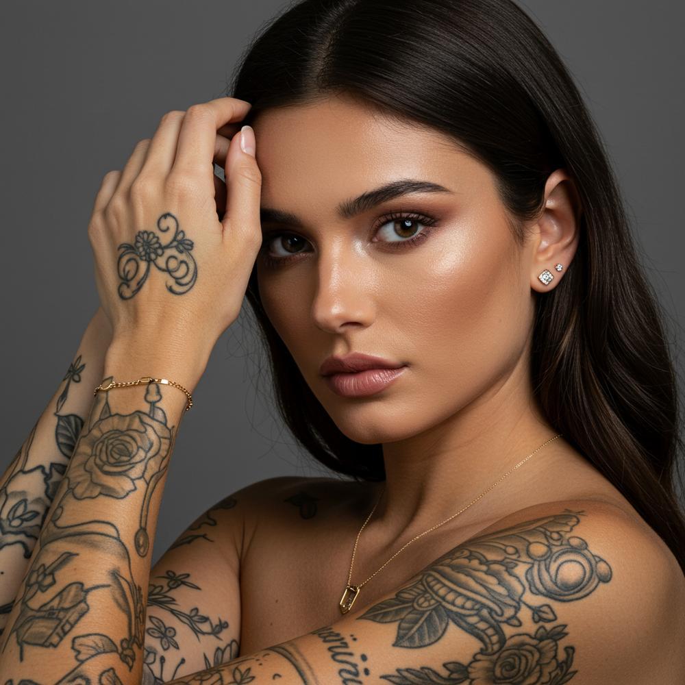 Woman styling delicate gold jewelry with a floral arm tattoo