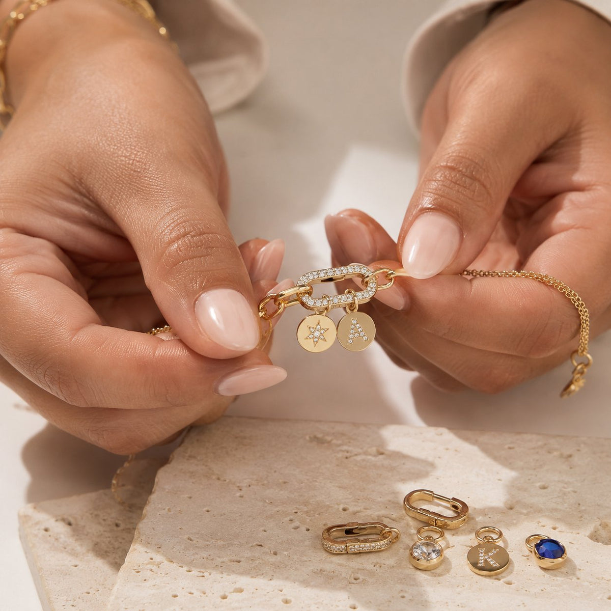 A stack of elegant gold bracelets showcasing the art of the clasp with hidden charms dangling from the closures.