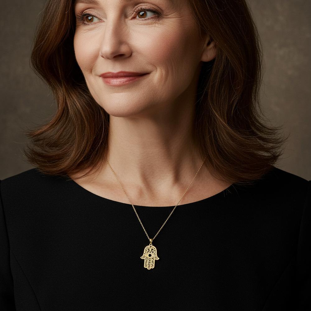 A stunning gold Hamsa pendant featuring an eye symbol in the center, representing protection and spirituality.